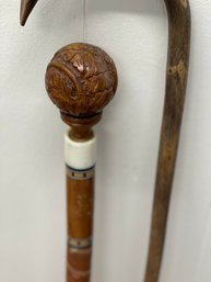 Two Canes, One Ornately Carved Ball Top With Inlaid Stone And Wood, One Very Primitive