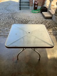 White Square Metal Outdoor Table With Glass Top Decorated With Delicate Scrolling Motif