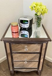 Wood And Mirror Drawer Single Door Side Table With Alarm Clock, Candle, And Vase