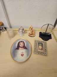 2 Small Angel Statues, 1 Jesus Plate, 1 Jesus Framed Pictures, 1 Small Candle, 1 Stand With A Plasitc Decor