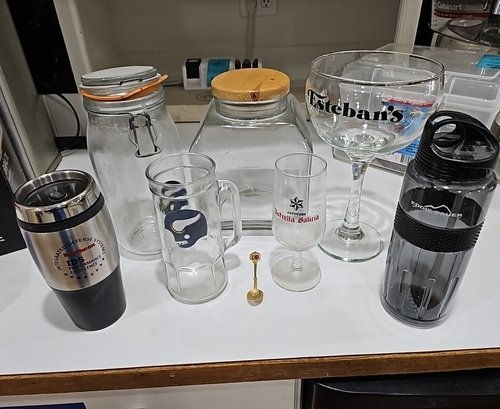 R10 Lot To Include Glass Jars, Glass Drink Ware, Plastic Bottles, And Small Spoon