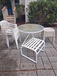 Rm.00. Outdoor Table, Four Plastic Chairs, Six Plastic Stools, And Large Stool.
