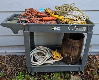 R00 Grey Cart With Multiple Extention Cords, Rope, Hoses, Gloves, And Small Barrel