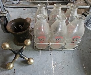 R0 Lot To Include Vintage Glass Milk Containers, Cast Iron Mortar And Pestle, And Large Brass Jack Decor