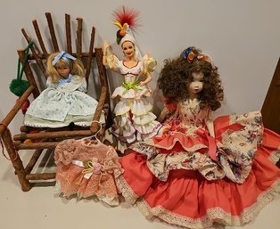 R1 Two Ceramic Dolls And One Plastic Doll, Small Wooden Chair, And Doll Clothing Wall Decor