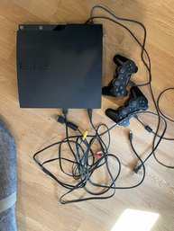 Sony Playstation 3 With Two Controllers, A Powercord, An HDMI Cord, And AV Cord