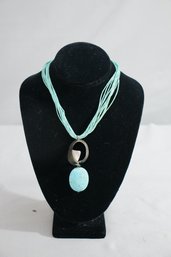 Faux Turquoise Egg With Abstract Metal Arc On Stratified Suede Lace Necklace