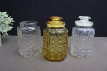 Group Of 3 Scroll Hexagonal Glass Lidded Canisters, 2 Clear And 1 Amber (one Clear Missing Top)