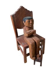 Enigmatic Folk Art Carved Wood Sculpture Of Man With Crossed Arms Sitting  In A Chair With A Smaller Chair