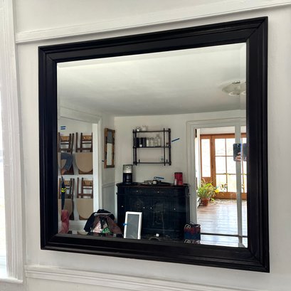A Wood Framed Black Mirror With Beveled Trim