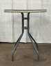 A Small Glass Topped Bistro Table With Braided Trim