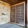 A Front Door  With Side Lite Panel And Distinctive Midcentury Wood Privacy Screens