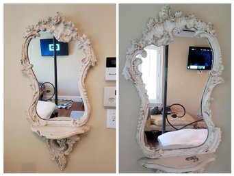 A Pair Of White Distressed Mirrors With One Shelf
