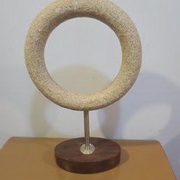 Modern Sculpture Ring Of Composite Material On Wooden  Stand