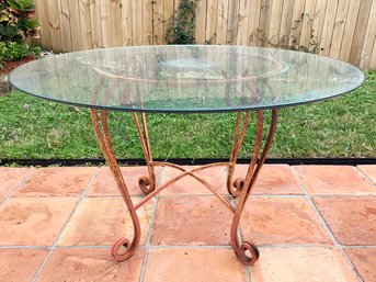 A Glass Top Dining Table With Wrought Iron Base