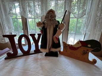 Santa In Emerald Green Coat, With JOY Sign, And Wooden Sled Decoration
