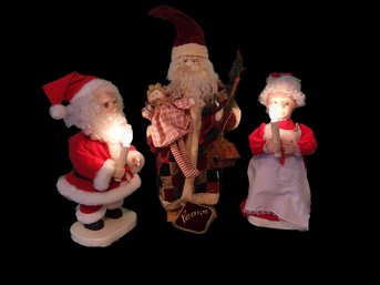 A Tall Santa, And Mr. And Ms. Clause Holding Lighted Candles.