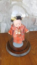 A Japanese Child Doll Displayed Under Glass Dome Case