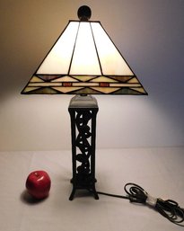 An Open Work Wrought Iron Table Lamp With Arts And Crafts Stained Glass Shade