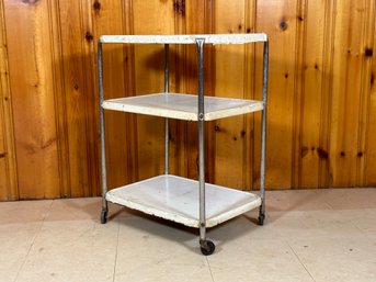 A Vintage Industrial Rolling Cart With Three White Enamel Shelves