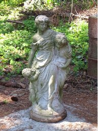 A Concrete Statue Of A Woman With Children