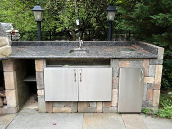 A Granite And Stone Outdoor Counter With Sink, Stainless Cabinet, And Trash Cabinet - Right Of Pizza Oven