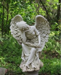 A Resin Statue Of A Winged Angel Seated On A Stump