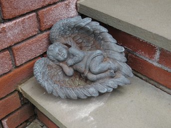 A Green Resin Cherub Sleeping In Wings