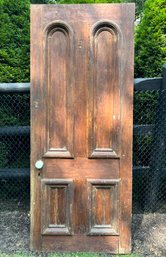 An Antique Four Panel Door With Arched Top Panels And A Marble Doorknob