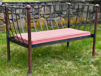 A Vintage Wrought Iron Garden Bench With Striped Cushion