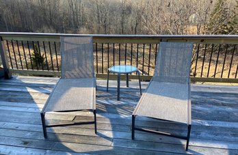 Two Chaise Lounge Chairs And A Round Glass Top Table