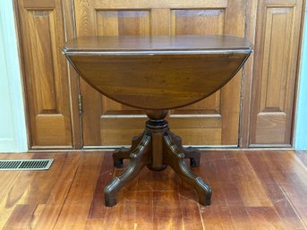 A Small Vintage Drop Leaf Table With An Oval Top, Turned Column & Decorative Feet