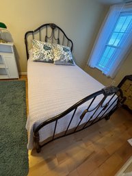 A FULL SIZE WROUGHT IRON BED WITH BEDDING