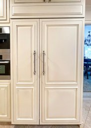 A Sub Zero Refrigerator With Paneled Wood Doors And Upper Cabinets