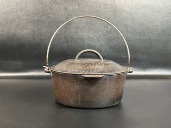 A Vintage Cast-Iron Dutch Oven With Wire Bail Handle