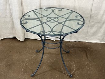 A Glass Topped Table With A Scrolled, Painted Metal Frame