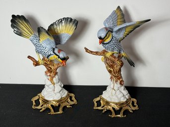 A PAIR OF PORCELAIN BIRDS ON GILT METAL STANDS, ONE BIRD LOST BEAK