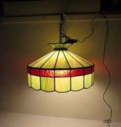 A Stained Glass Hanging Light Fixture In Reds & Greens