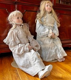 A Pair Of Porcelain Dolls On Metal Stands