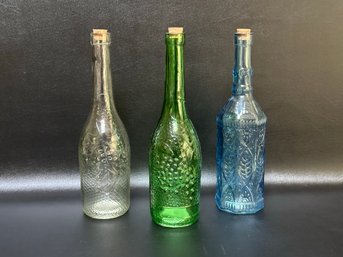 A Trio Of Colorful Bottles With Embossed Patterns