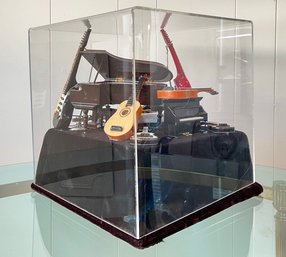 A Miniature Musical Instrument Tableau, Under Lucite On Velvet Base