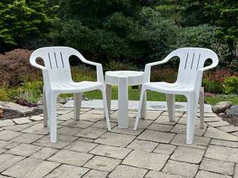 A Pair Of Stackable White Plastic Chairs & A Small Matching Table