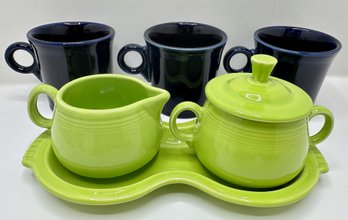 7 Fiesta Ware Pieces: Green Sugar Bowl With Creamer On Tray & 3 Blue Mugs