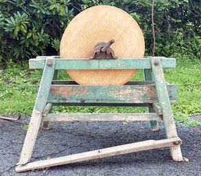 An Antique Grindstone On Wood Stand