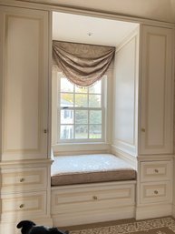 A Built - In Window Seat With Storage Cabinets & Cushion & Shade