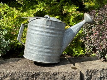 A Watering Can In Galvanized Metal With A Rounded Bottom