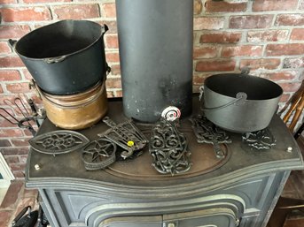 WROUGHT IRON TRIVETS, TWO CAST IRON POTS, AND ONE COPPER POT