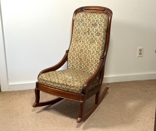 A Small Antique Rocking Chair With A Wood Frame & Tapestry Upholstery