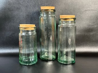 A Set Of Green Glass Canisters With Cork Stoppers