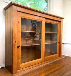 A Vintage Oak Cabinet With Glass Paneled Sliding Doors